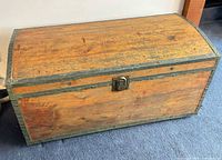 Front view of wood steamer trunk showing domed lid, front hasp and metal trim