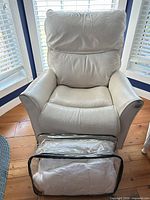 Front view of white leather recliner with duvet in storage bag placed in front