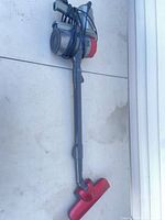 Full view of red and gray Xtreme corded stick vacuum with cord wrapped and floor head attached