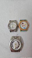 Three watch heads: Waltham analog, orange cartoon analog, large silver analog
