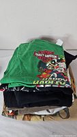 Stack of four folded graphic t-shirts showing colors and layers