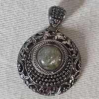 Front view of sterling silver pendant showing cabochon and ornate border