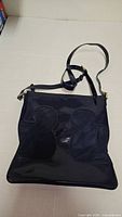 Front view of navy patent leather Tory Burch crossbody showing canvas insets and overall shape