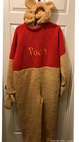 Full view of Pooh costume hanging, showing red and tan color blocks and attached mittens