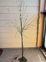 Full view of 5 ft black metal LED blossom tree with white blossoms on stand