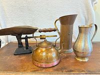 Group view of scale, copper kettle, hammered brass pitcher, tall cylindrical pitcher