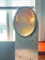 Front view of oval shell cameo against ruler showing height around 1.25 in