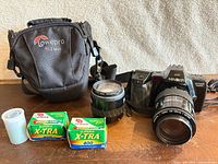 Full lot: camera body with attached lens, second lens, strap, Lowepro bag, two boxed film canisters, one empty film canister