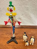 Murano glass clown and three ceramic penguins together