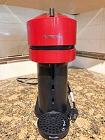 Front view showing red Nespresso head, black body, Breville drip tray, power cord