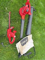 Toro blower/vac, tubes, collection bag, Homelite hedge trimmer on grass