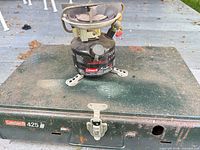 Coleman 400 series stove sitting on closed Coleman 425 green metal case