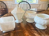group shot of four white glass and ceramic pieces on table