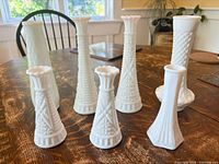 All seven white milk glass vases grouped on table