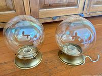 Front view of both smoky amber glass globe fixtures showing glass condition and brass tone bases