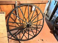 Full view of wagon wheel leaning against wooden backdrop
