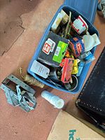 Overview of blue tote with boxed nails, staples, tins, twine and loose hardware