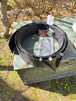 Coiled black edging with stakes package on table