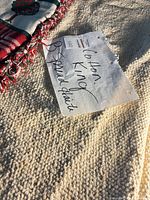 Close-up of red/green holiday runner atop cream bedspread showing textures and tag