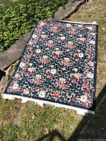Full view of floral area rug laid flat outdoors showing overall design, colors and fringe
