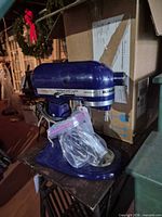 Side view of dark purple KitchenAid stand mixer with bagged attachments