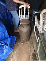 full view of rusted steel milk can with lid in storage area