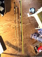 Four fishing rods laid beside measuring tape for length reference