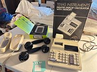 Overall lot view showing calculator, calculator box, Nokia phone box, two BellSouth phone bases, two black receivers