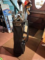 Full view of black golf bag holding assorted clubs
