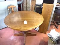 Round oak pedestal dining table with tag on top
