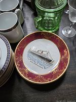 Front view showing plate design, rim colour, gilt detail, ship image