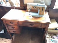 Full view of sewing machine mounted in wooden cabinet