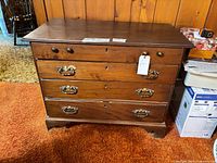 Front view of walnut dresser showing four drawers and brass handles