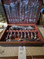 Open case showing wrapped knives, forks, spoons, and presentation box