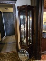 Full view of tall mahogany corner curio cabinet with glass panels and door