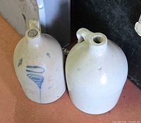 Two gray stoneware jugs side by side showing glaze colors and cobalt decoration