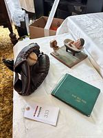 Lot overview showing glove with ball, wooden figurine, green booklet