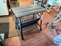 Full view of side table showing wood plank top, rattan spindle sides, lower shelf, and rope-twist legs