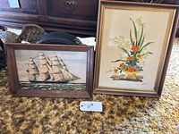 Both framed needlepoint artworks side by side on floor