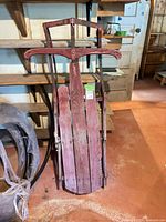 Full view of red wooden sled leaning against wall