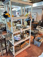 full view of five-tier white plastic shelving unit with contents present for scale