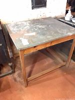Angled view of full table showing wood frame, metal top, lower shelf