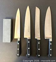 Group view of four knives and sharpening stone, blades up
