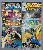 All four comic books laid out: Battlestar Galactica #1, Marvel Super Heroes Secret Wars #2, Dazzler #34, The New Mutants #37