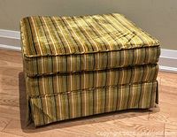 Full view of ottoman at angle showing upholstery and skirt