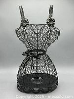Front view of black wire dress form showing overall shape and scrollwork