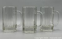 Front view of three identical clear glass beer mugs