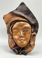 Front view of molded leather face wall hanging showing overall form and two-tone colouring