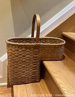 Basket positioned on stairs showing L-shaped profile and handle