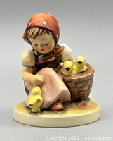 Front view of figurine showing girl, chicks, basket, and base